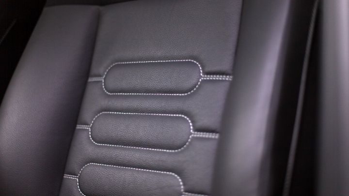 Ein schwarzer Auto-Ledersitz mit gestepptem Design liegt im Innenraum eines Fahrzeugs und zeigt einen gepflegten Zustand.