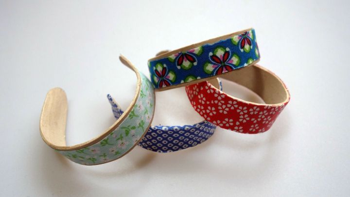 Bunte Armreifen aus Eisstielen liegen auf einer hellen Oberfl&auml;che und zeigen verschiedene kreative Muster.