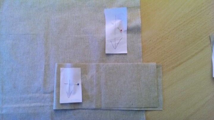 Auf einem Tisch liegen zwei St&uuml;cke Stoff mit markierten Fadenl&auml;ufen, um die Ausrichtung f&uuml;r das N&auml;hen zu kennzeichnen.