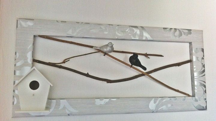 Ein dekorativer Bilderrahmen zeigt zwei V&ouml;gel auf &Auml;sten, umgeben von einem minimalistischen wei&szlig;en Hintergrund.