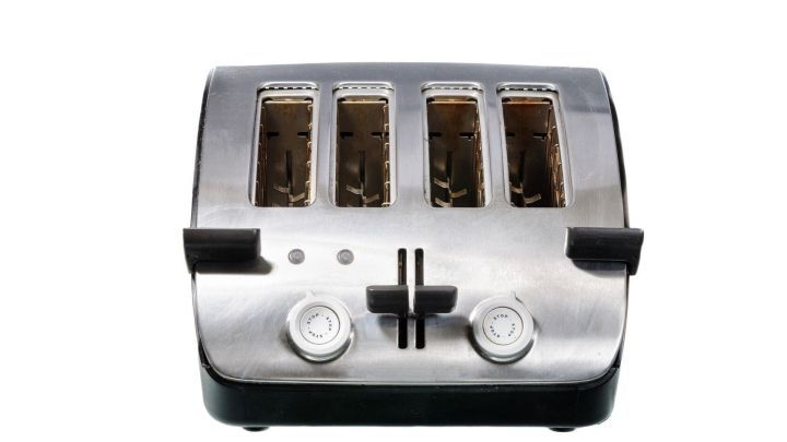Ein gl&auml;nzender Toaster poliert das Chrom, w&auml;hrend er auf einer sauberen, wei&szlig;en Oberfl&auml;che steht.