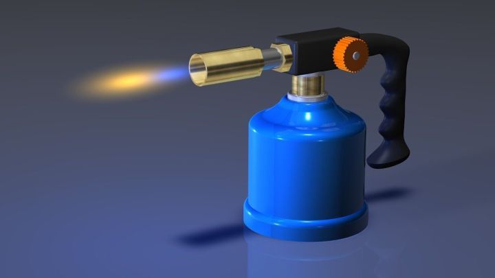 Ein blauer Gasbrenner steht stabil auf einem Tisch und erzeugt eine Flamme, w&auml;hrend er bereit ist, Urinstein zu entfernen.