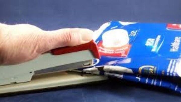 Eine Hand verwendet einen Tacker, um einen Tetrapak zu verschlie&szlig;en und spart Platz im M&uuml;lleimer.