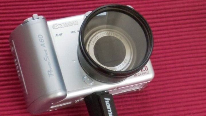 Eine Kamera mit flexiblen Armen liegt auf einem roten Hintergrund, bereit f&uuml;r Fotoaufnahmen der Frag-Mutti-Community.