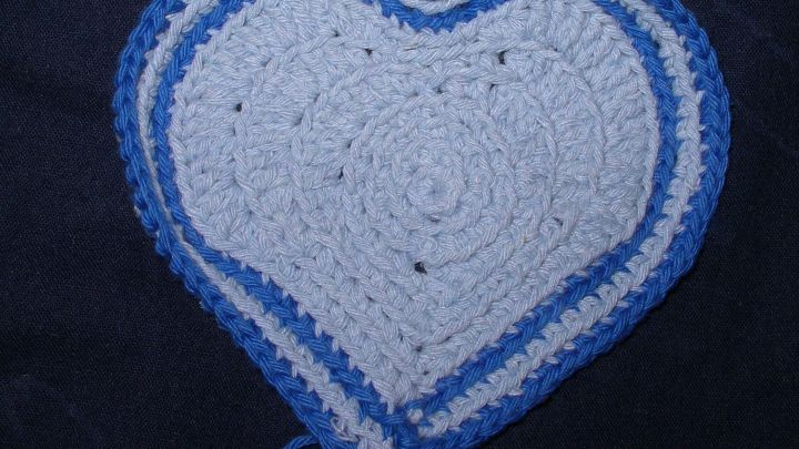 Ein geh&auml;keltes Herz in Blau und Wei&szlig; liegt auf einem dunklen Hintergrund und zeigt klare, runde Muster.