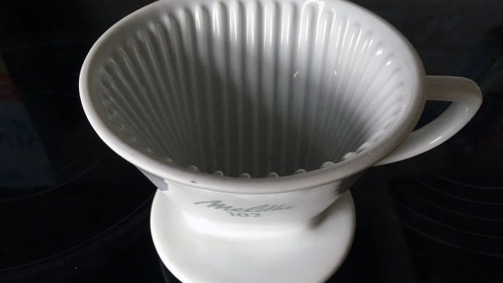 Ein Handfilter steht auf einer dunklen Oberfl&auml;che, bereit zum Zubereiten von Kaffee in einer gem&uuml;tlichen K&uuml;che.
