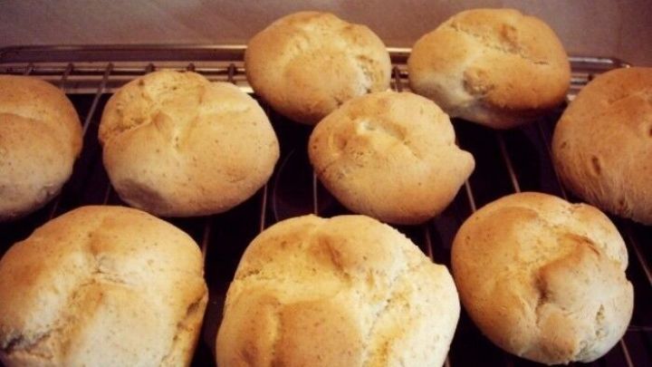 Frisch gebackene Br&ouml;tchen aus Hefeteig ruhen auf einem Rost, goldbraun und knusprig, ideal f&uuml;r jede Mahlzeit.