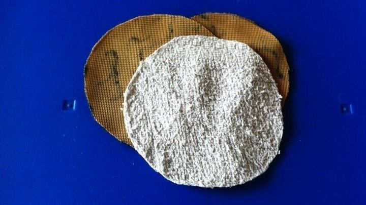 Wiederverwendbare Kosmetikpads liegen auf einer blauen Oberfl&auml;che, umgeben von nachhaltigen Materialien, die ihre Umweltfreundlichkeit betonen.