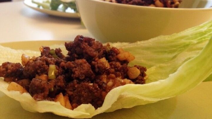 Salat-Wraps liegen auf einem Teller, w&auml;hrend gef&uuml;llte Wraps mit einer herzhaften Mischung am Tisch stehen.