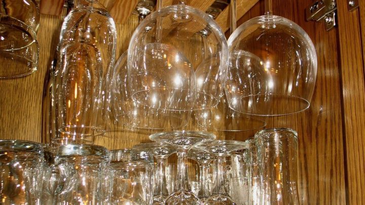 Gl&auml;ser mit Stiel h&auml;ngen platzsparend in einem Holzregal, w&auml;hrend normale Gl&auml;ser ordentlich darunter aufgereiht stehen.