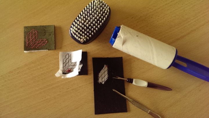 Eine Rolle mit klebrigem Band entfernt Stickvlies von einer schwarzen Karte, um es f&uuml;r kreative Projekte zu nutzen.