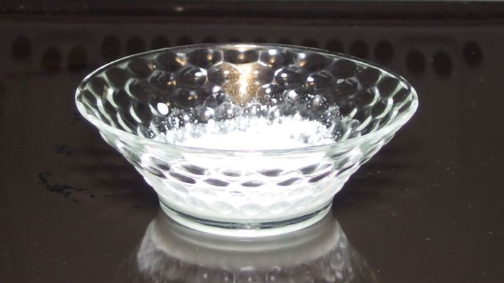 Eine klare Sch&uuml;ssel steht leer auf einer dunklen Oberfl&auml;che, bereit, mit Waschpulver zur Backofenreinigung gef&uuml;llt zu werden.