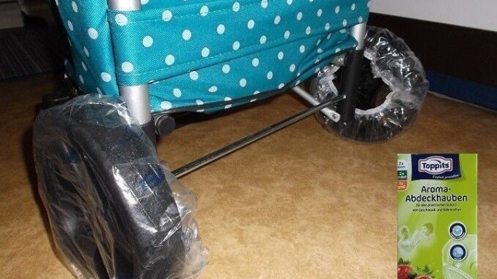 Ein Einkaufstrolley mit nassen Rollen steht auf einem beige gefliesten Boden, w&auml;hrend die Rolle in Schutzfolie eingewickelt ist.