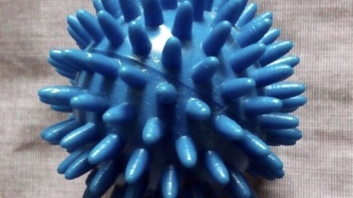 Ein blauer, stacheliger Ball liegt auf einem grauen Untergrund, ideal zur Linderung von Juckreiz ohne Aufkratzen.