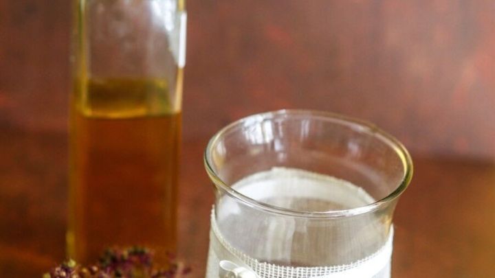 Eine Glasvase mit Wasser und Dekoration steht neben einer Flasche &Ouml;l, um Kalkr&uuml;ckst&auml;nde in Deko-Wasser-Schalen zu reduzieren.