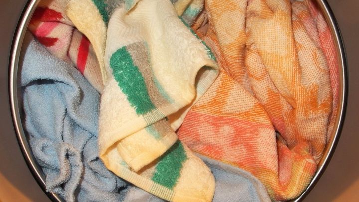 In einer Waschmaschine befinden sich bunte Handt&uuml;cher, die darauf warten, mit warmem Wasser gewaschen zu werden.