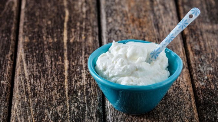 Eine kleine, t&uuml;rkisfarbene Schale mit einer cremigen Paste steht auf einer rustikalen Holzoberfl&auml;che.