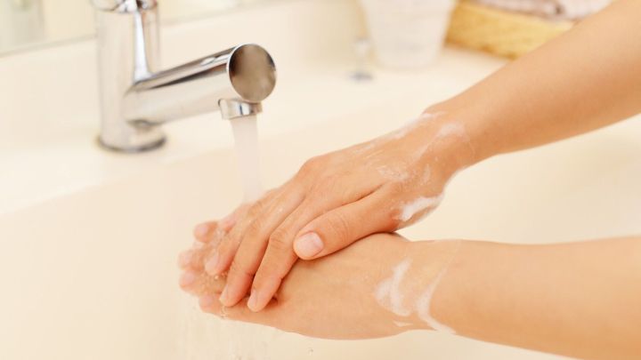 H&auml;nde mit Seife werden unter einem Wasserhahn gewaschen, um clever Wasser zu sparen. Der Waschbeckenbereich ist hell und ordentlich.