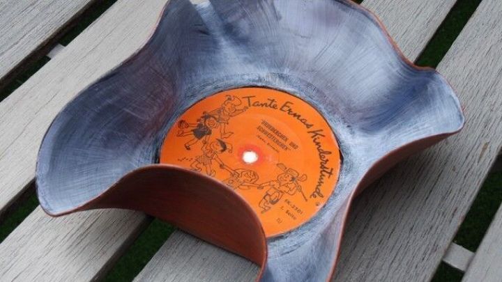 Eine dekorative Schale aus einer Schallplatte liegt auf einem hellen Tisch, kreativ gebogen und k&uuml;nstlerisch gestaltet.