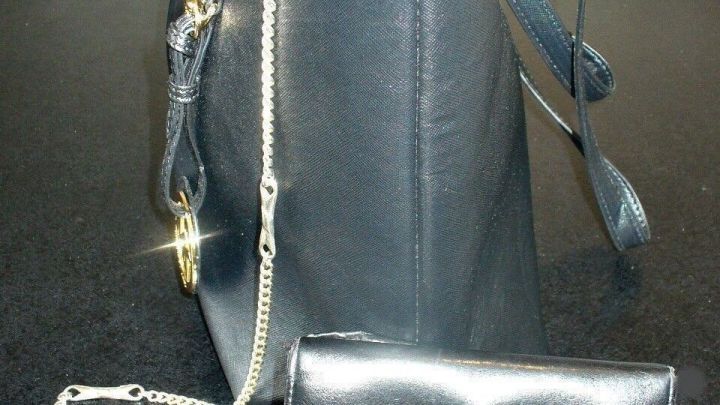 Ein schwarzes Portemonnaie ist an einer Kette befestigt, die am Innenrand einer Handtasche h&auml;ngt.