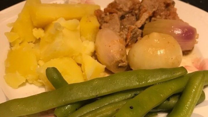 Ein Teller mit Stifado, einer Fleischgerichtvariation, begleitet von Kartoffeln und gr&uuml;nen Bohnen, in einer heimischen K&uuml;che.