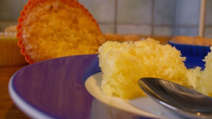 Kokosmuffins auf einem Teller, frisch serviert und teilweise gegessen, in einer hellen K&uuml;che mit blauen Fliesen.