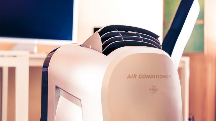 Ein mobiler Klimaanlagen-Block sorgt f&uuml;r frische Luft in einem modernen Raum mit Fernseher im Hintergrund.