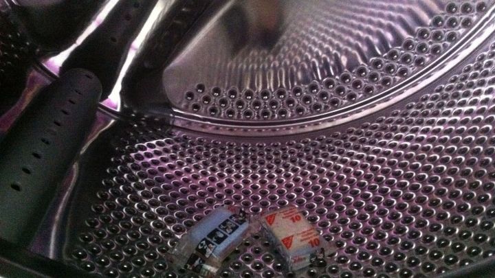 Eine gl&auml;nzende Waschmaschine zeigt die Trommel von innen, w&auml;hrend zwei farbige Gegenst&auml;nde darin liegen und sie sauber wirkt.