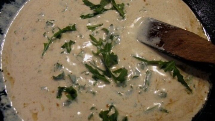 Eine cremige Chicor&eacute;e-Suppe mit frischem Rucola wird in einer Sch&uuml;ssel angerichtet, bereit zum Servieren.