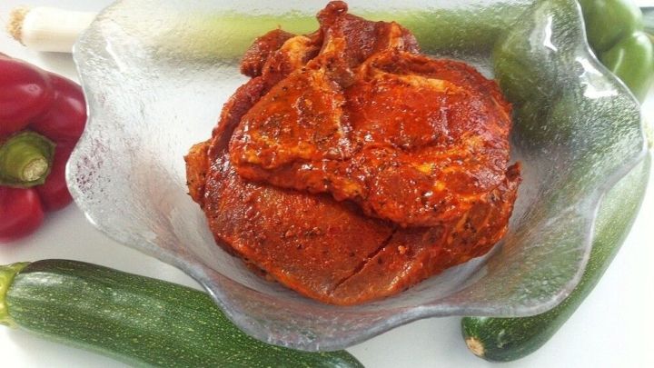 Eine sch&auml;lchen mit w&uuml;rziger Grill-Marinade liegt im Vordergrund, umgeben von frischem Gem&uuml;se wie Zucchini und Paprika.