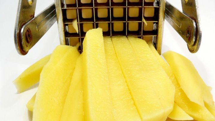 Ein Gem&uuml;seschneider presset Kartoffeln in gleichm&auml;&szlig;ige St&auml;bchen, die ordentlich vor dem Ger&auml;t liegen und den Schneideprozess zeigen.