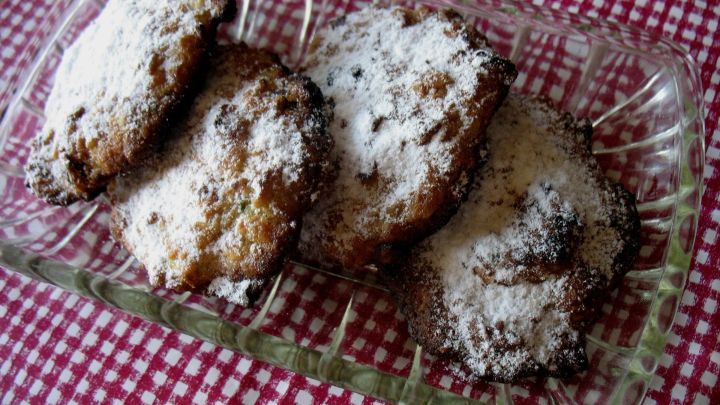 Zucchini-Apfel-Hafer-Cookies liegen auf einem Glasplatte, mit Puderzucker best&auml;ubt, vor einem karierten Hintergrund.