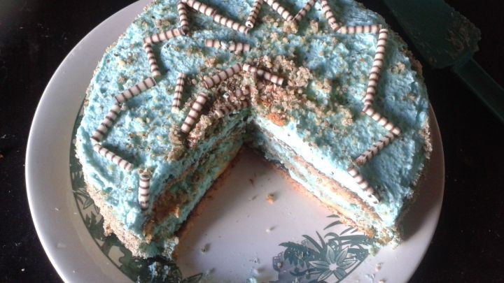 Eine farbenfrohe Haselnuss-Sahnetorte mit Bananen, teilweise angeschnitten, auf einem dekorativen Teller.