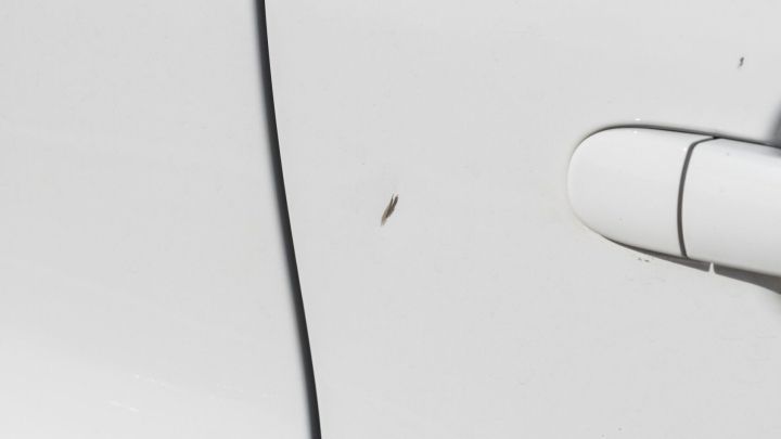 Ein wei&szlig;er Autolack mit einem kleinen Kratzer neben der T&uuml;r&ouml;ffnung, der eine Ausbesserung ben&ouml;tigt.