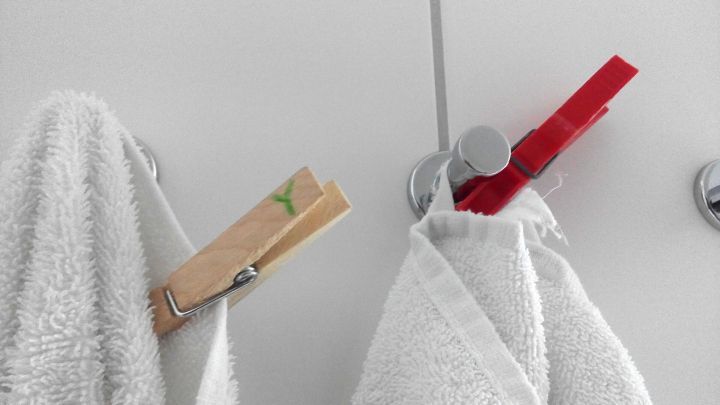 Wei&szlig;e Handt&uuml;cher h&auml;ngen an einem Haken, jeweils mit einer W&auml;scheklammer befestigt, auf einem hellen Hintergrund.