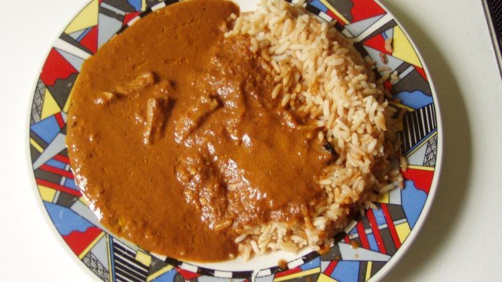 Ein Teller zeigt saftige H&auml;hnchenfajitas mit braunem Sauce, serviert neben Reis, farbenfrohes Design umrandet das Gericht.