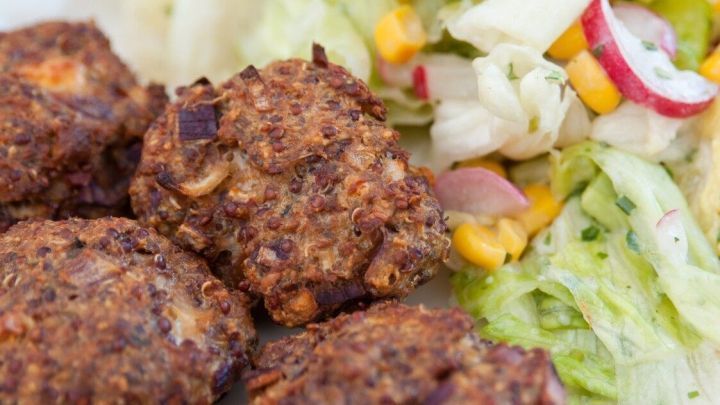 Saftige orientalische Frikadellen liegen auf einem Teller, umgeben von frischem Salat mit buntem Gem&uuml;se.