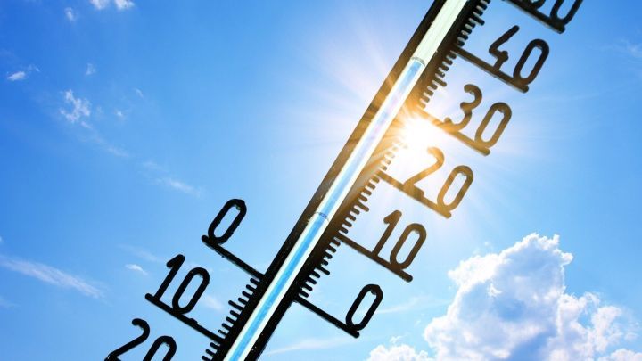 Ein Thermometer zeigt hohe Temperaturen an, w&auml;hrend die Sonne am blauen Himmel strahlt, ideal bei Hitze.