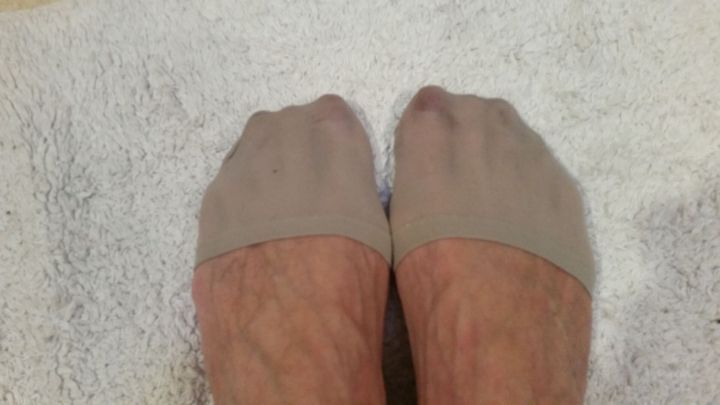 Beige Strumpfhosen umschlie&szlig;en F&uuml;&szlig;e, w&auml;hrend sie auf einem weichen Handtuch liegen, umgeben von einem neutralen Raum.