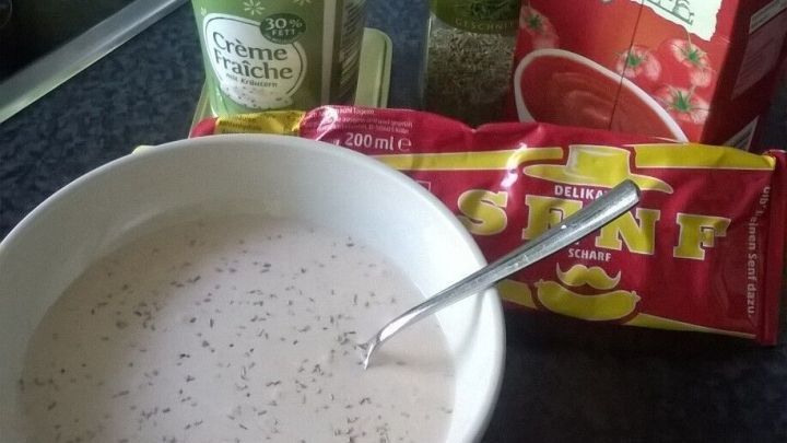 Eine Sch&uuml;ssel mit einer cremigen Sauce steht auf einer dunklen Arbeitsfl&auml;che, w&auml;hrend verschiedene Zutaten wie Tomatenpassata und Gew&uuml;rze daneben liegen.