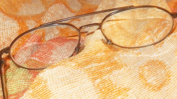 Eine Brille liegt auf einem gemusterten Tuch, bereit, mit Wasser und Spiritus gereinigt zu werden.