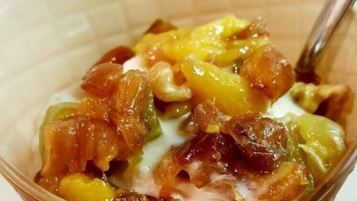 Eine Sch&uuml;ssel mit cremigem Joghurt wird mit einem knackig-fruchtigen Topping aus bunten Fr&uuml;chten und N&uuml;ssen garniert.