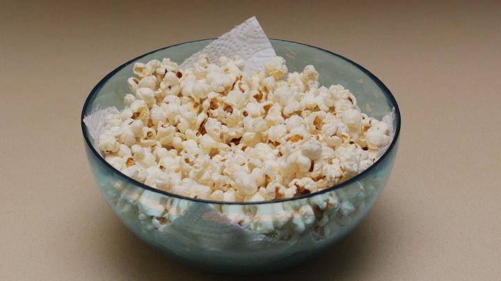 Eine Glassch&uuml;ssel mit frisch zubereitetem Popcorn steht auf einer K&uuml;chenarbeitsfl&auml;che, kalt und bereit zum Servieren.