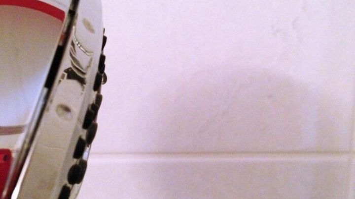 Ein Duschkopf wird in Richtung der Glasw&auml;nde gehalten, um sie schnell sauber und trocken zu machen. Die W&auml;nde sind wei&szlig; fliesenverkleidet.