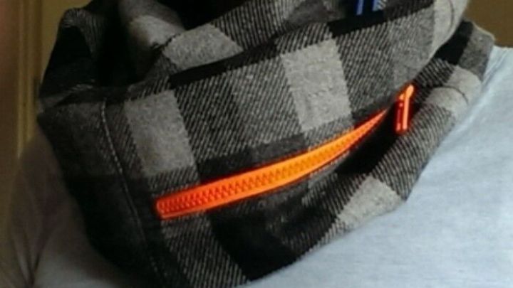 Ein Loop mit Rei&szlig;verschlussfach liegt um den Hals, w&auml;hrend die Person bequem darin kleine Gegenst&auml;nde verstaut.