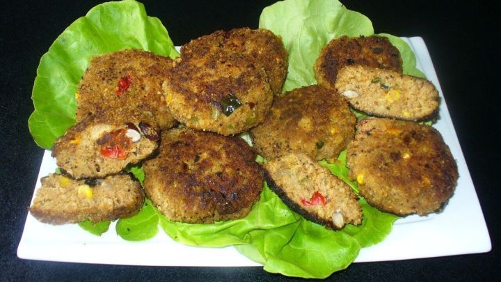 Tex-Mex-Frikadellen liegen auf einem wei&szlig;en Teller, umgeben von frischen, gr&uuml;nen Salatbl&auml;ttern, appetitlich pr&auml;sentiert.