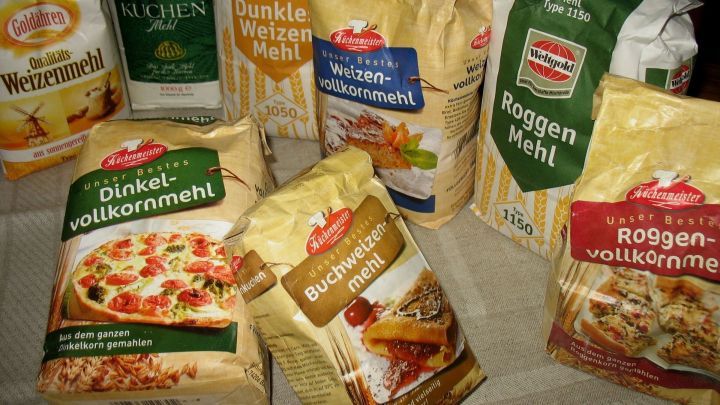 Eine Vielzahl von Mehlpackungen steht auf einem Tisch, bereit f&uuml;r die Verwendung in verschiedenen Backrezepten.