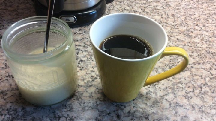 Eine gelbe Tasse mit schwarzem Kaffee steht neben einem Glas Zucker auf einer K&uuml;chenarbeitsplatte, bereit f&uuml;r den Morgen.