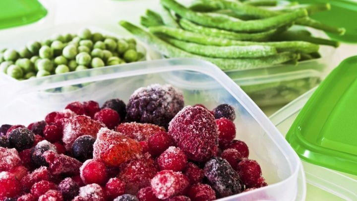 Gefrorene Beeren in einer transparenten Box liegen neben gefrorenem Gem&uuml;se in einem hellen, organisierten K&uuml;chensetting.