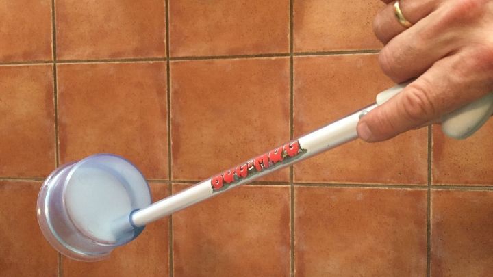 Ein Bug-Mug wird benutzt, um kleine Spinnen und Tierchen zu fangen. Die Hand h&auml;lt es &uuml;ber einem gefliesten Boden.